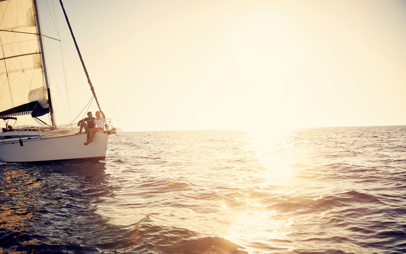 Couple sitting on a sailboat at sunset on the ocean